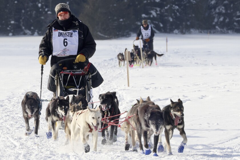 Two mushers cross lake.