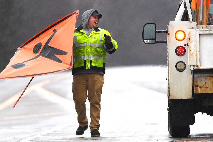 Man holding highway sign in the rain.