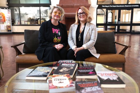 Two authors sit together in front of their books