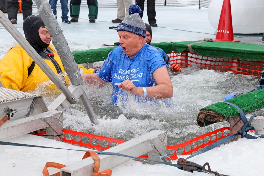 People jump into the water during the Polar Plunge event on Pelican Lake.