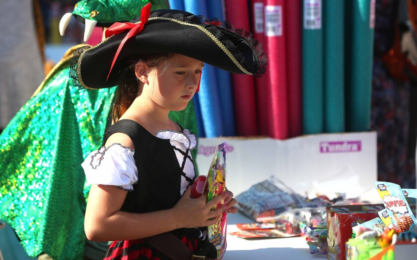 Girl holds prizes while wearing a costume and standing in line