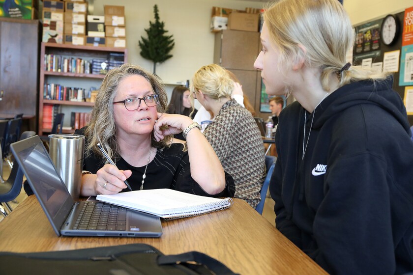Octagon adviser, Katie Thompson, left, goes over some questions with Michelle Fudally during journalism class at Northwestern High School