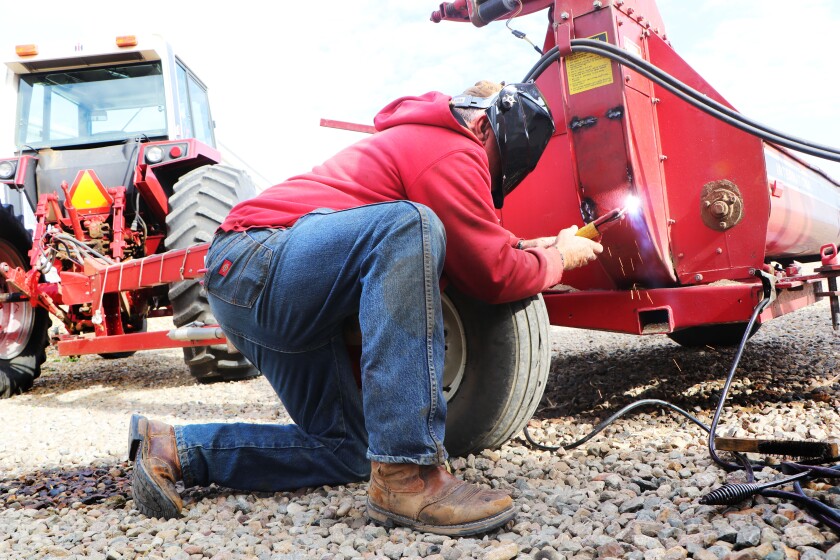A man makes a quick weld on a plate on his corn chopper in the middle of the 2022 corn harvest.