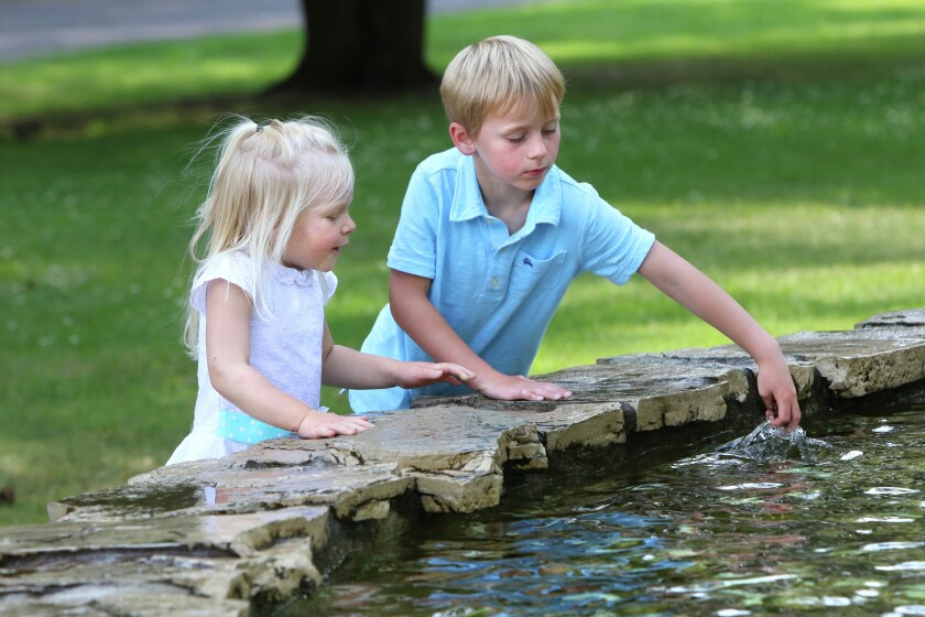 Aubry and Jude Johnson dip there hands into the fountain Tuesday at Gregory Park in Brainerd. (Kelly Humphrey, Brainerd Dispatch)