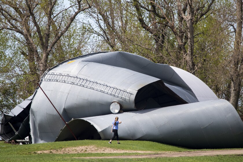 A woman surveys damage to a silo at a farm outside Blomkest Friday, May 13, 2022. Strong winds associated with a storm Thursday evening caused damage throughout the region.