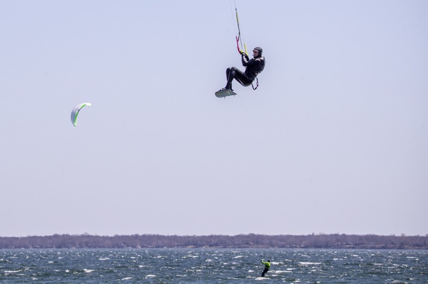 Victor Ruotti, above, of Madison, Wisconsin, soars in the sky above kiteboarding friend Eric Spottke of Loretto as they spend the afternoon kiteboarding in high winds along Green Lake outside Spicer on Saturday, May 7, 2022.