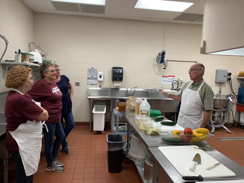 People in a kitchen preparing food to cook.
