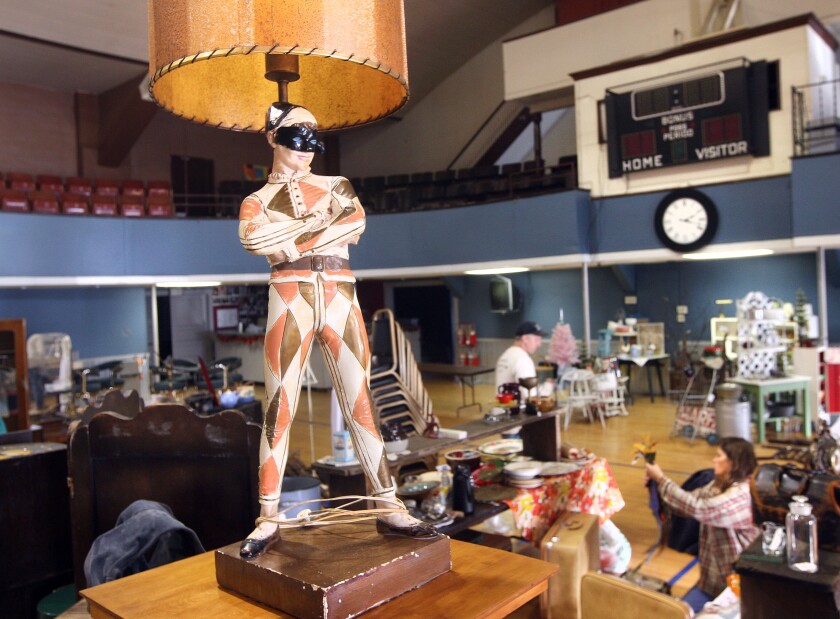 A coral and tan jester lamp rests on a platform while other vintage items are seen in the background.