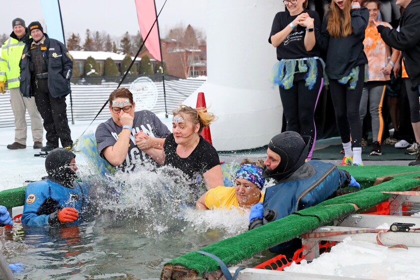 People jump into the water during the Polar Plunge event on Pelican Lake.