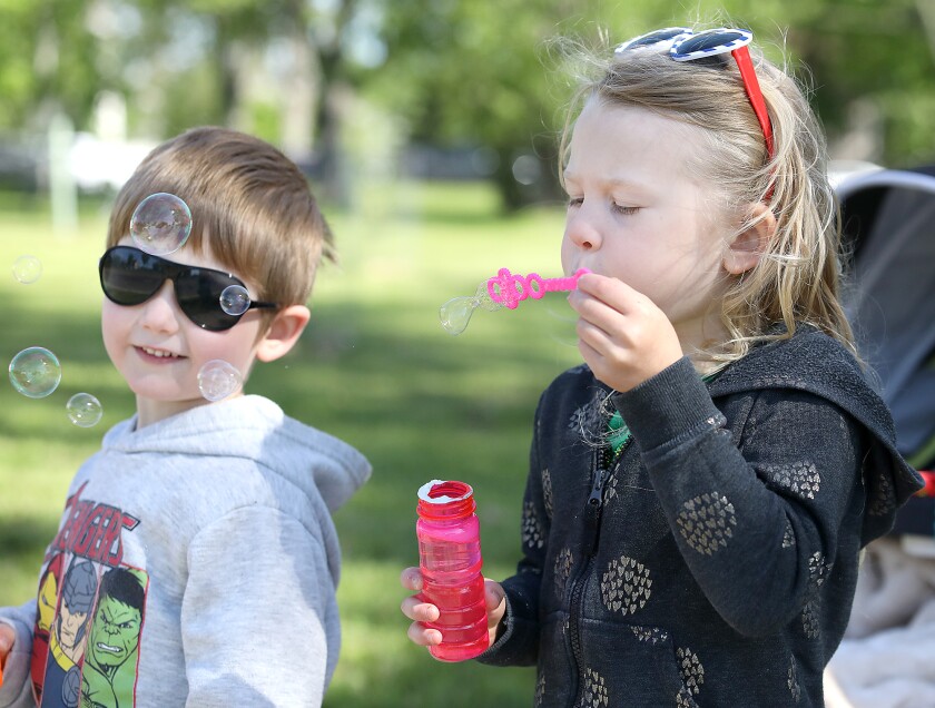 Marlowe Tupy, 5, blows bubbles in front of her brother, Arthur Tupy, 4, as they wait to cheer on runners