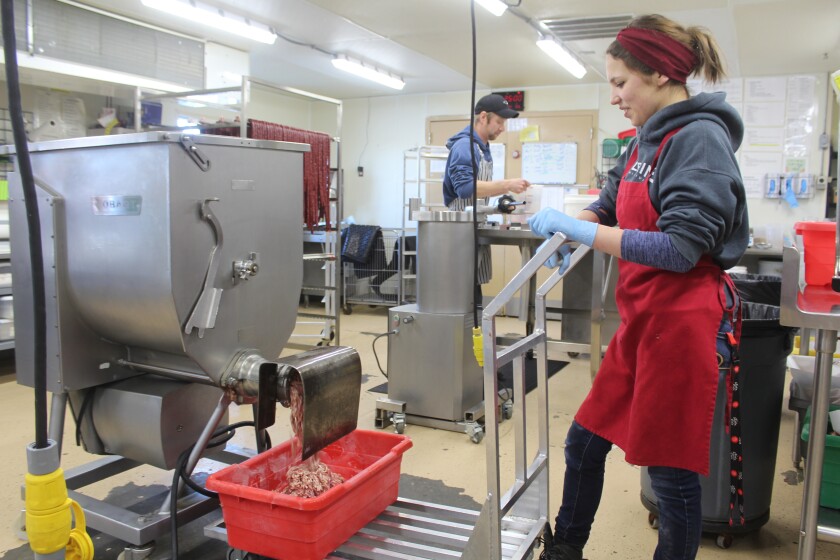 It's a dirty job, but Anna Baburkina (red apron) knows how to do it and do it right -- that's why she's been made the plant manager for Dickinson's Wurst Shop, producing sausage known 'round the world. (Iain Woessner / The Dickinson Press)