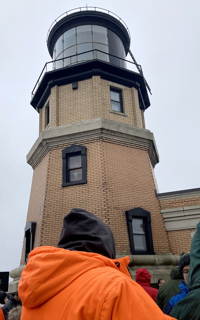People standing outside of a lighthouse at a ceremony.
