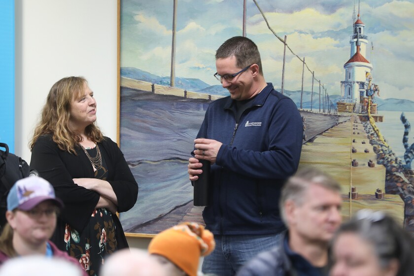 A woman and man standing and laughing before an indoor event.