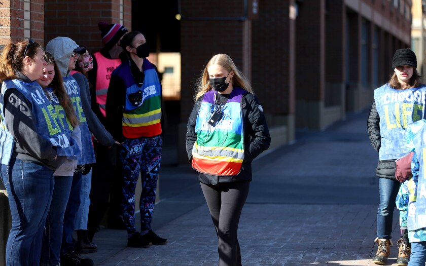 a clinic escort walks between protesters