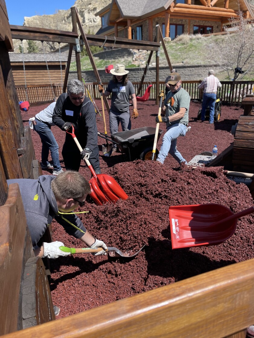 Shovel by shovel and rake by rake, a group of volunteers level out piles of new rubber mulch at Medora Children's Park on Saturday, May 14, 2022.