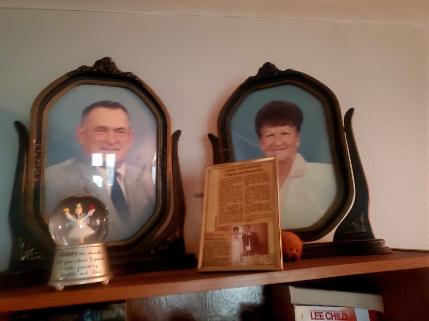 Portraits of two people sit on a shelf