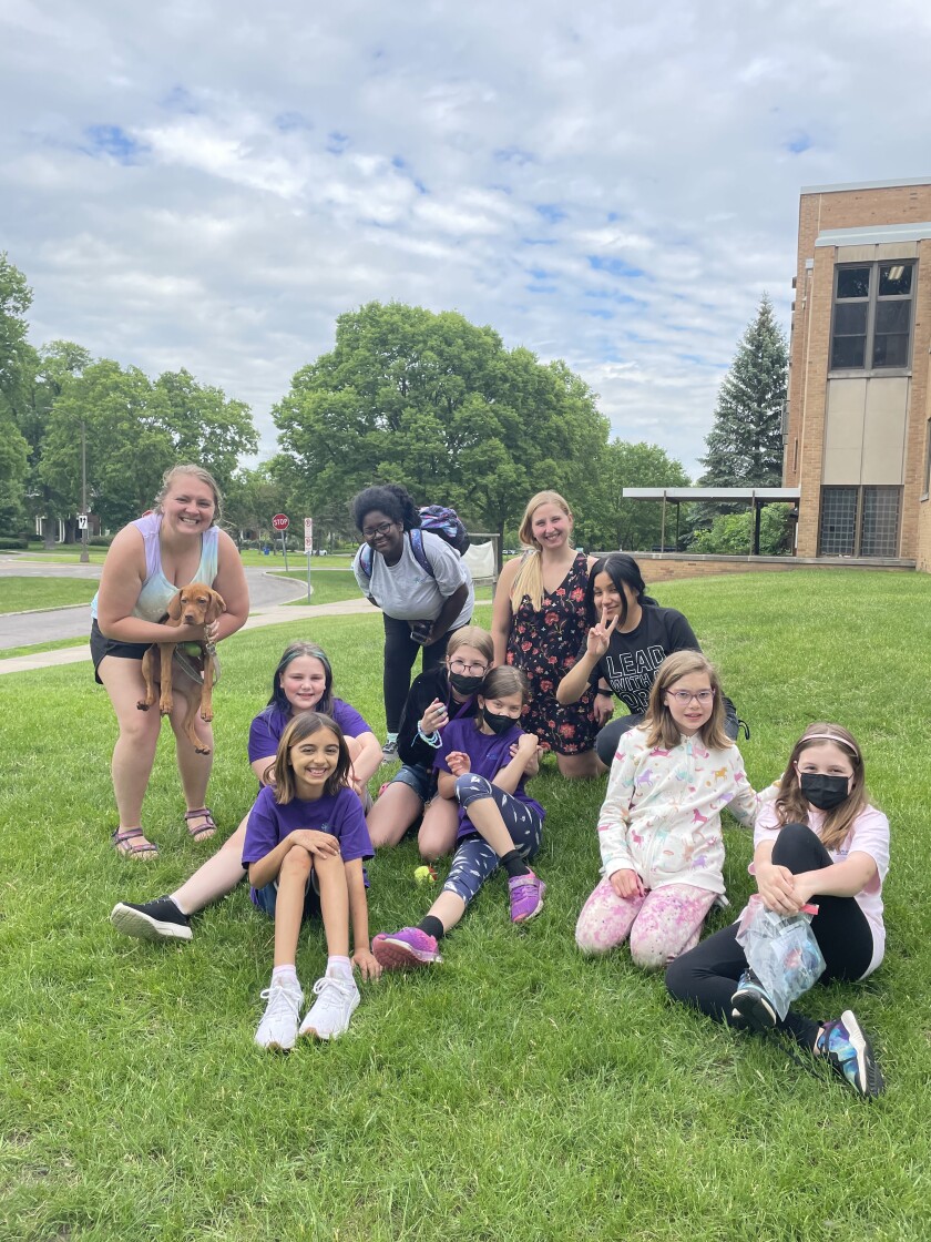 Katrina Friedrich, holding a dog, poses with the runners she coaches with Girls on the Run Minnesota.