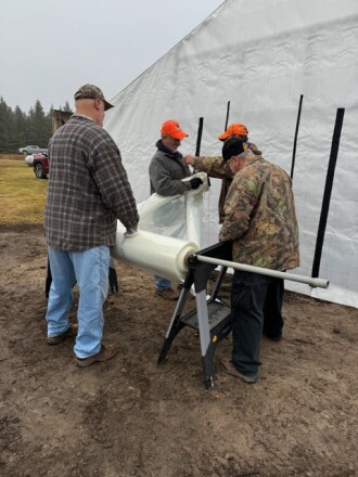 Volunteers setting up the plastic for the high tunnel.
