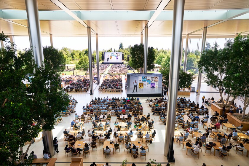 An overview shows row upon row of people and giant screens as people gather for the June 6, 2022, Apple Worldwide Developers Conference. 