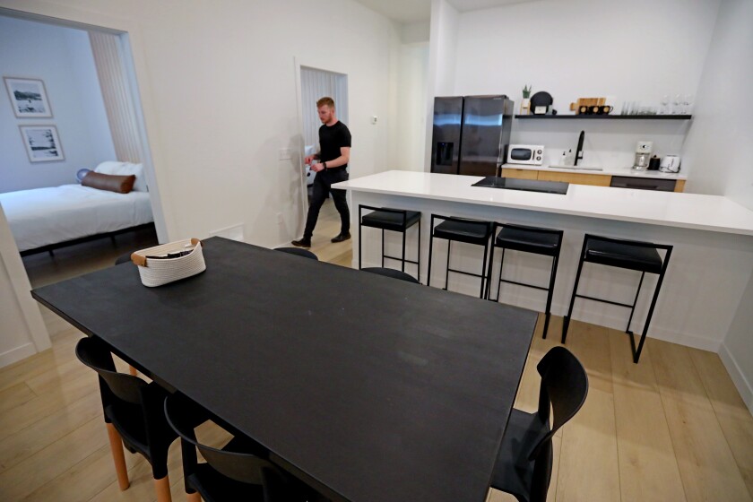 A black table and chairs sits in a room on light wooden floors.