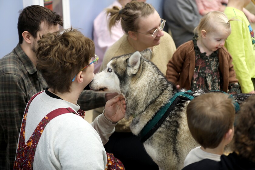 A dog getting ready to lick a woman's face at an indoor event.