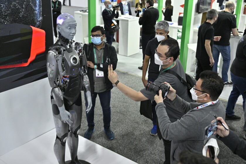 A life-sized humanoid robot is photographed by people at the CES show.