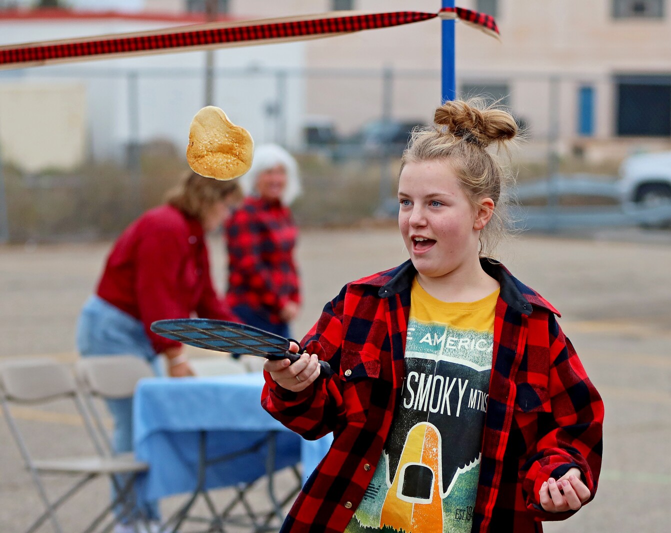 A girl flips a flapjack with a paddle.
