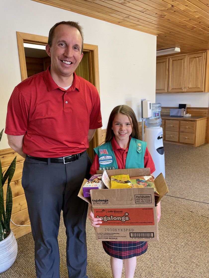 Executive Director Carter Fong of the Dickinson Area Chamber of Commerce smiles for the camera with Girl Scout Ellisyn Ahmann.