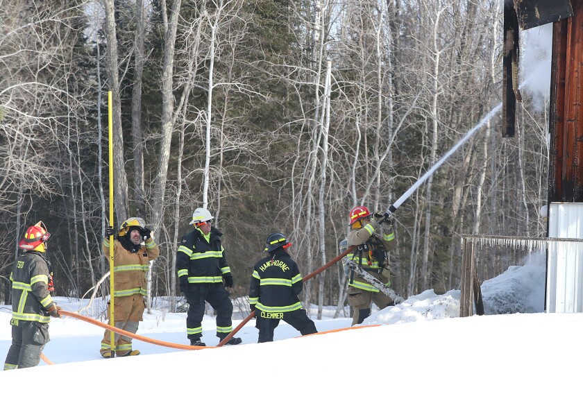 Firefighters hold a hose line.