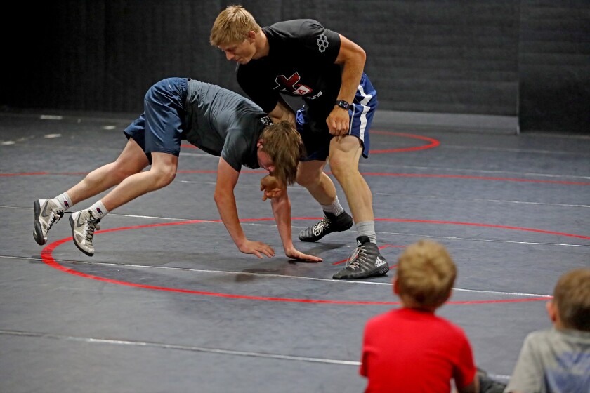 Hayden Zillmer, top center, demonstrates a wrestling move with Isaiah Jillson, left, while coaching kids at the Scoring Edge Wrestling Center.