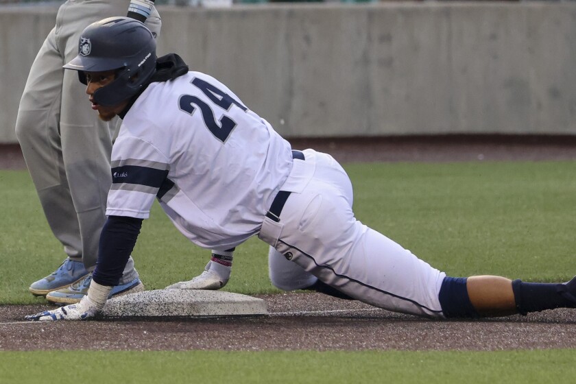 Baseball players in white and blue uniforms playing a game at outdoor stadium