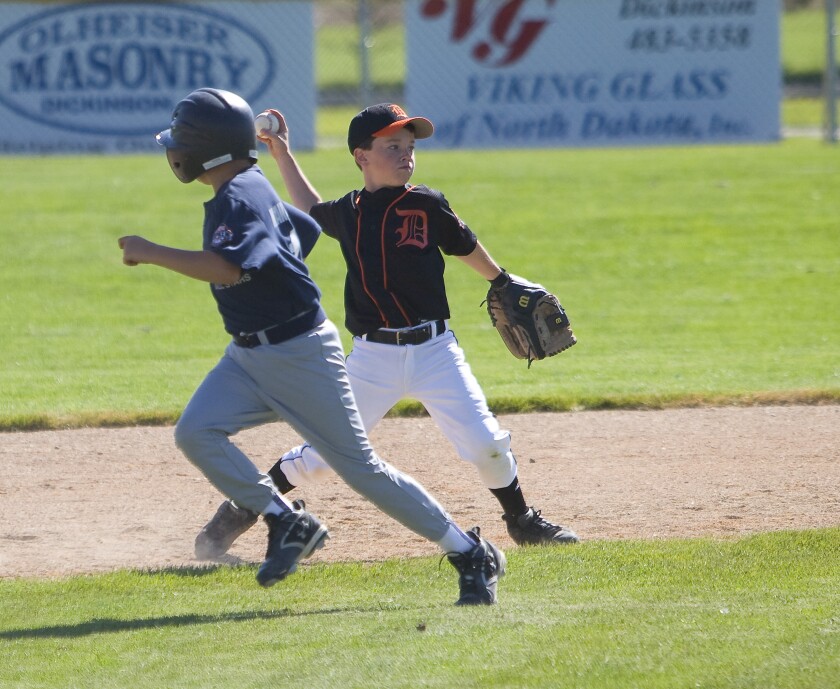 A young boy from a Dickinson baseball team throws a pass during a summer game.