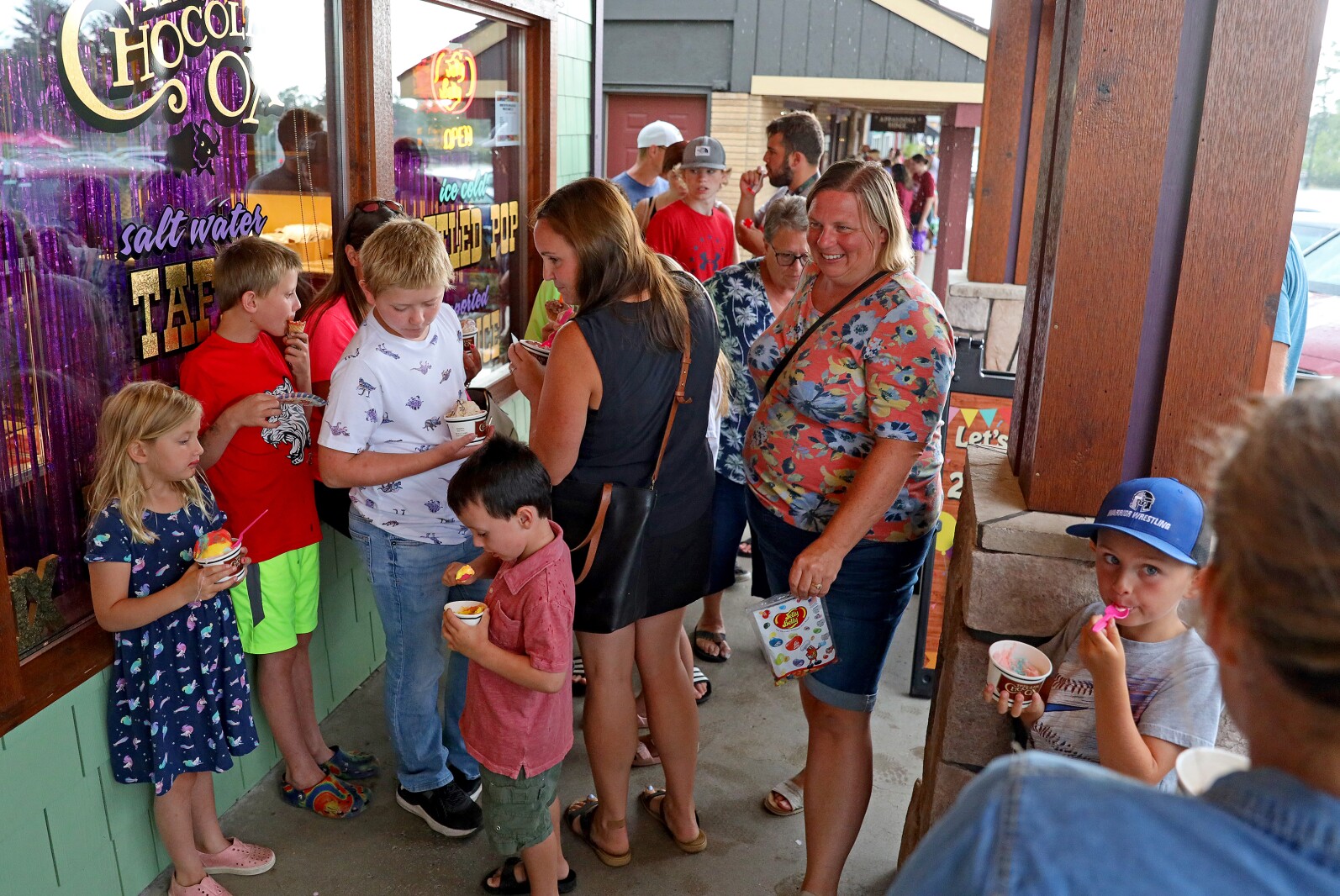 People eat ice cream on the covered walkway to avoid the rain Wednesday, Aug. 24, 2022, outside of The Chocolate Ox in Nisswa.