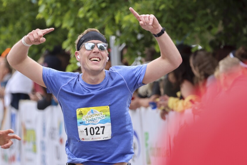 Athletes running and celebrating at the finish line area of Grandma's Marathon