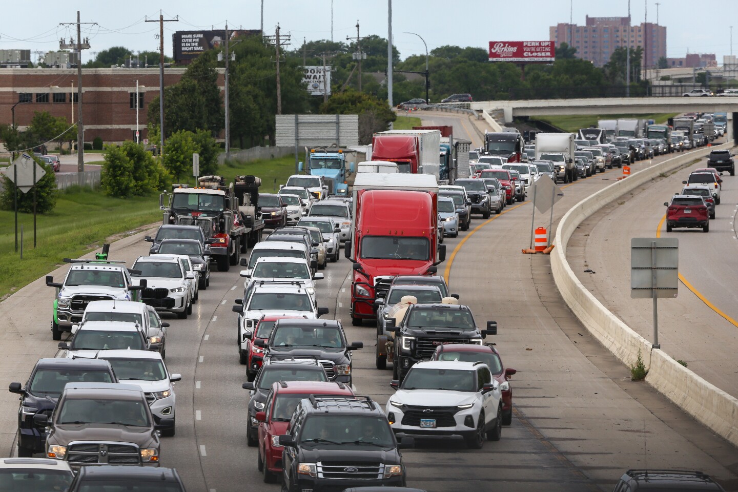 A mix of cars are stuck in a traffic jam on an interstate highway passing through a city.