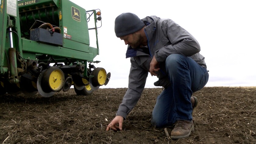 Jared Goplen bends down to inspect soil.