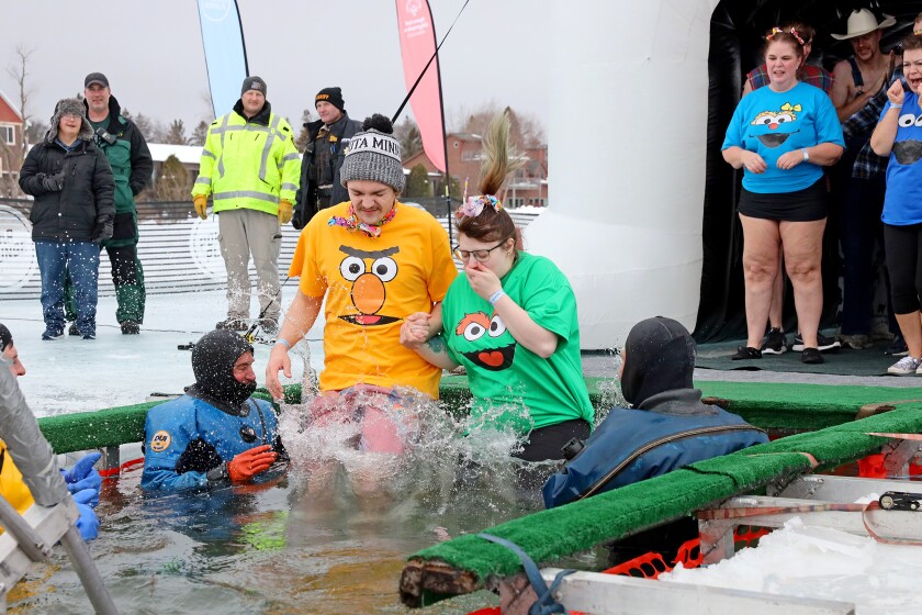 People jump into the water during the Polar Plunge event on Pelican Lake.