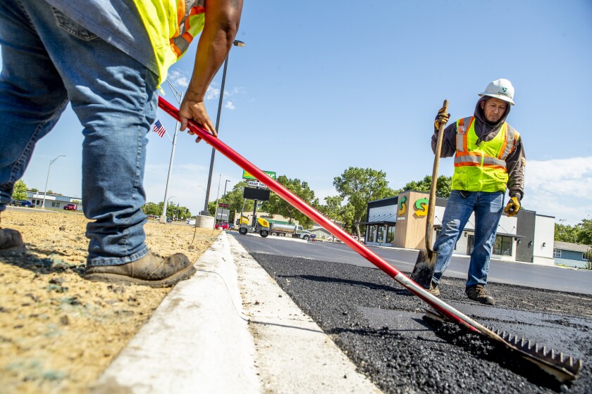 Duininck worker Jose Miguel, at right, watches Lorenzo Lara smooth out asphalt at the new Subway location along 1st Street South on Wednesday, June 29, 2022.