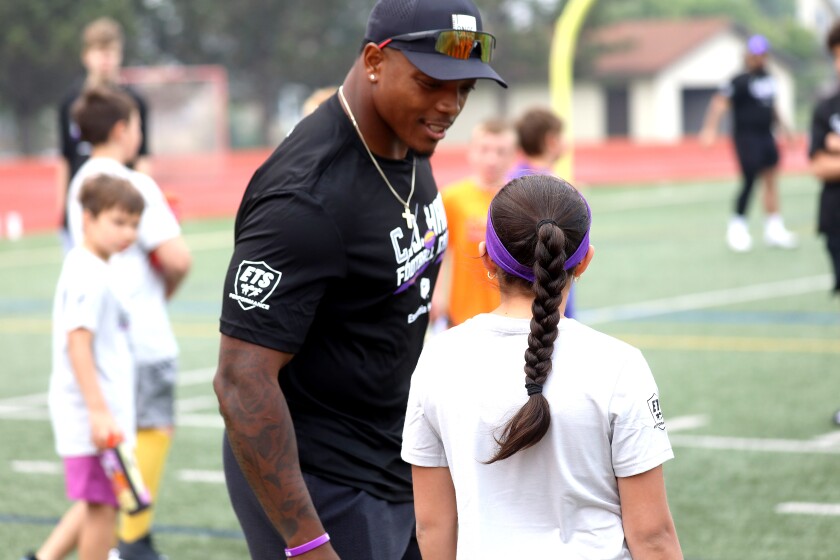 A pro football player listening while a young girl asks him a question.