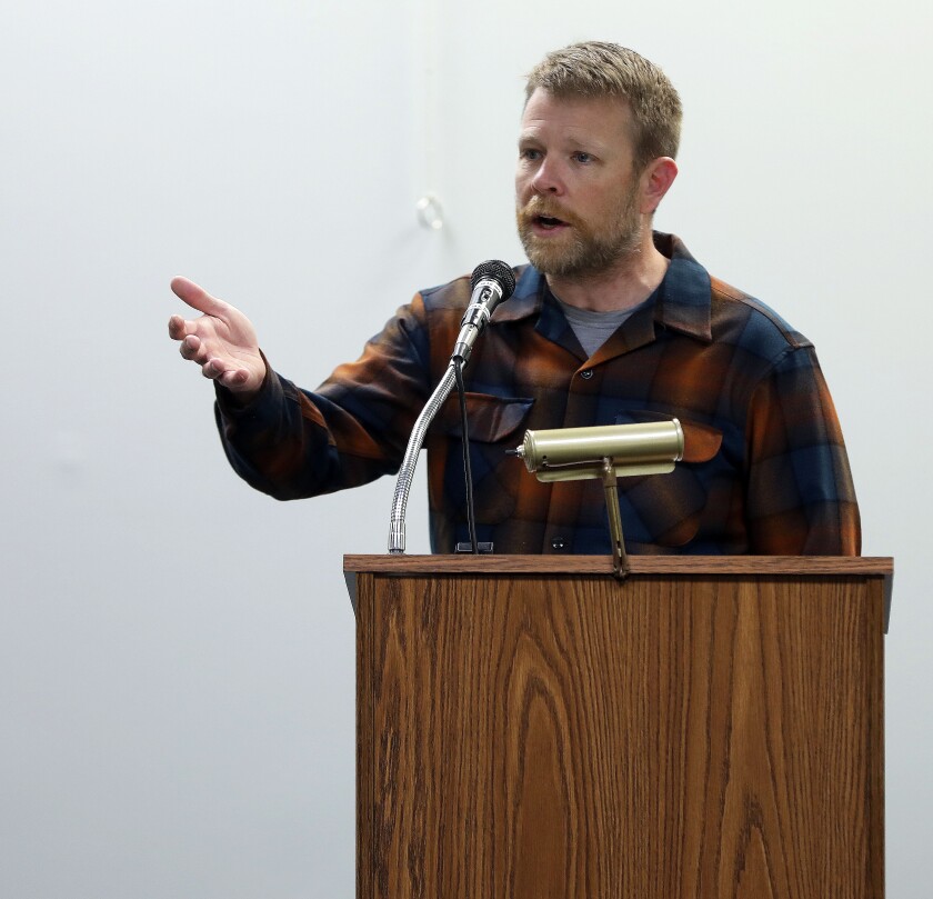 A man gesturing while speaking at a podium.