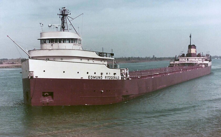 Great Lakes Freighter se jménem "Edmund Fitzgerald" viditelné na přídi. Červená malovaná loď má přední a zadní nástavby.