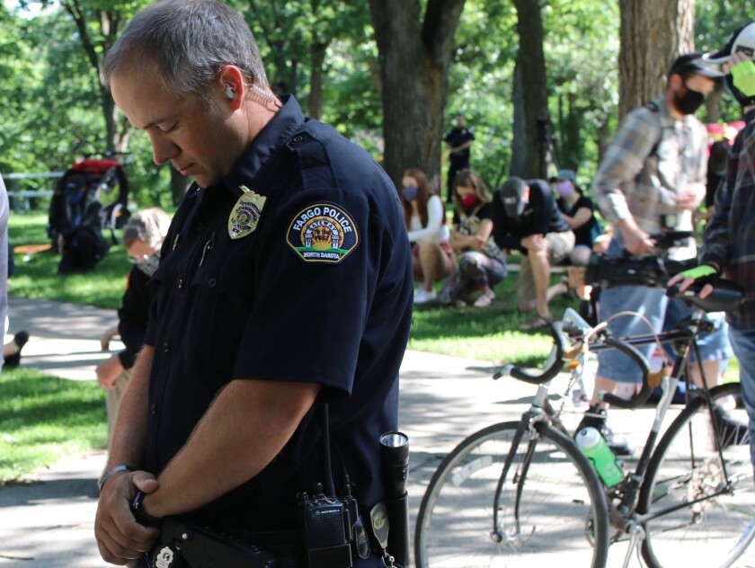 Fargo Police officer bowing his head during the minutes of silence for George Floyd during Juneteenth protest at Island Park..jpg