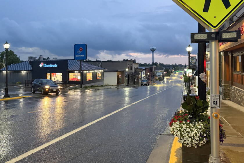 A vehicle turning onto a street in a town while rain falls.